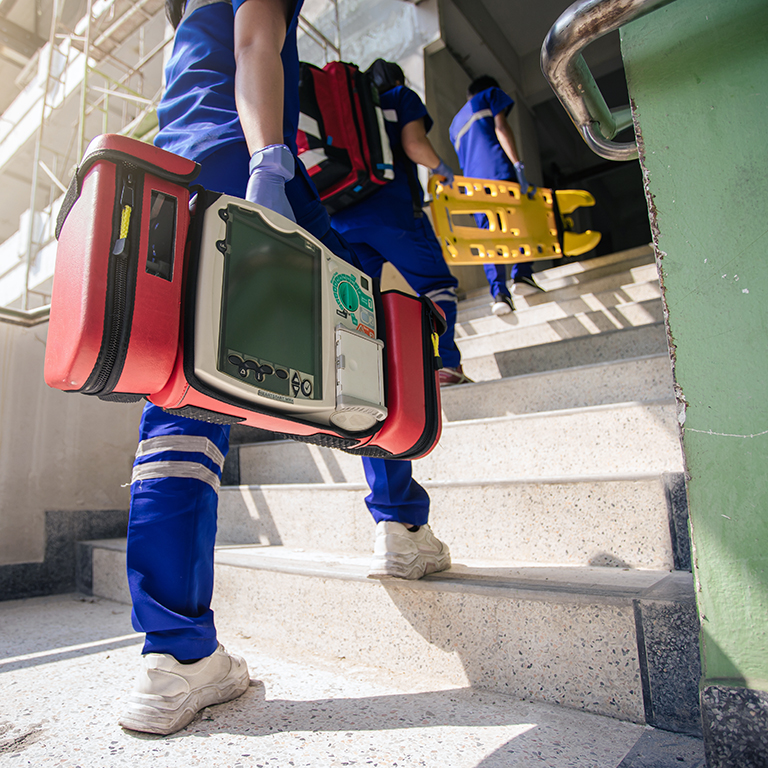Selective focus automated external defibrillator (AED) on hand of 
 paramedic. Emergency service team.